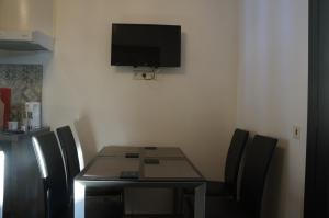 a dining room table with chairs and a television on the wall at Lavender Apartment in Argelès-sur-Mer