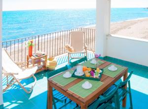 una mesa y sillas en un balcón con vistas a la playa en Le Terrazze di Apollo - Case Tilotta, en Marinella di Selinunte