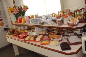 una mesa con muchos tipos diferentes de comida en ella en Hotel Tubarao, en Tubarão
