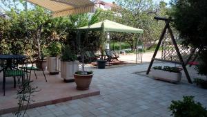 a patio with an umbrella and tables and chairs at House Lavanda in Rab