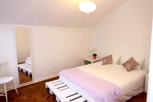 リスボンにあるWhite cosy apartmentの白いベッドルーム(ベッド1台、鏡付)