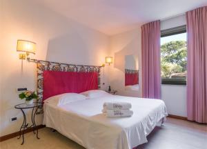 a hotel room with a white bed and white curtains at Hotel Villa Undulna - Terme della Versilia in Cinquale