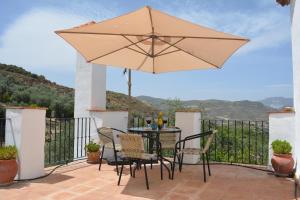 une terrasse avec une table, des chaises et un parasol dans l'établissement Casa Viñas de Vera, à Restábal