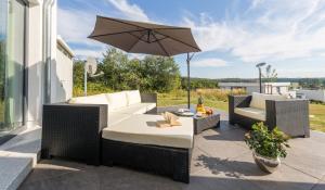 a patio with wicker furniture and an umbrella at Villa Blanca in Binz