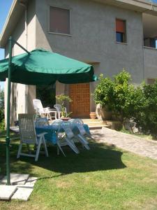 un tavolo e sedie sotto un ombrellone verde di Villa Peppe B&B a Francavilla al Mare