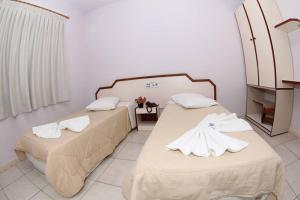 two beds in a hotel room with towels on them at Hotel Tubarao in Tubarão