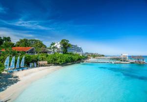 a beach with blue umbrellas and a resort at Sandals Ochi Beach All Inclusive Resort - Couples Only in Ocho Rios