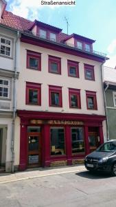 a red and white building with a car parked in front at Apartment Pension Sternchen in Erfurt