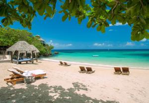 a beach with chairs and a umbrella and the ocean at Sandals Ochi Beach All Inclusive Resort - Couples Only in Ocho Rios
