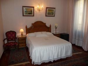 a bedroom with a white bed and a chair at Pension Lorea in San Sebastián