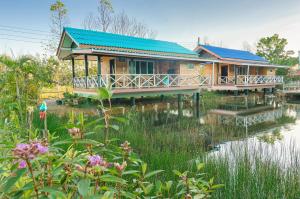 una casa con un techo azul junto a un cuerpo de agua en Ariya Garden Home en Chumphon
