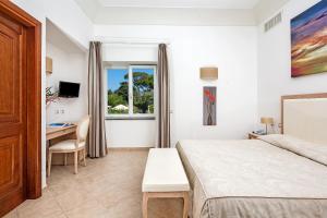 a bedroom with a bed and a desk and a window at Hotel Villa Ceselle in Anacapri