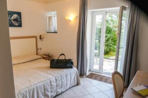 a bedroom with a bed and a door to a patio at Hotel Villa Ceselle in Anacapri