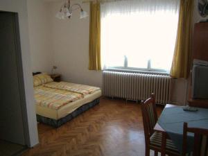 a bedroom with a bed and a table and a window at Pallósi Ház "A" in Sárvár