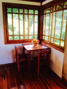 Lemon House Monteverde في مونتيفيردي كوستاريكا: طاولة وكراسي في غرفة بها نوافذ