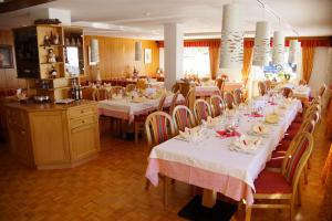 une salle à manger avec tables et chaises et nappes blanches dans l'établissement Pensione La Müda, à Badia