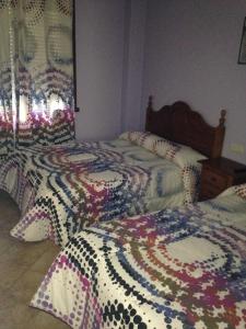 a bedroom with two beds with colorful comforters at Pension Meson Paz in Puentedeume