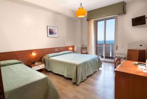 a hotel room with two beds and a large window at Hotel Continental Fano in Fano