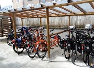 a group of bikes parked under a wooden structure at Logis Hôtel Restaurant LE MONARQUE 30 Parking Vélos Sécurisé in Blois
