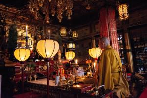 un monje está de pie en una habitación con luces en 高野山 宿坊 熊谷寺 -Koyasan Shukubo Kumagaiji-, en Koyasan