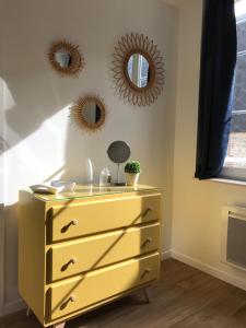 a yellow dresser in a room with two mirrors at Le Petit Nid d'Honfleur in Honfleur