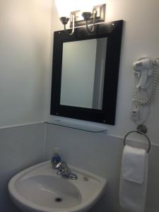 een badkamer met een wastafel, een spiegel en een telefoon bij Driftwood by the Sea Inn in Campbell River
