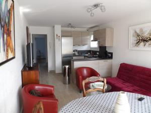 ein Wohnzimmer mit einem roten Sofa und einer Küche in der Unterkunft Clos Fleuri in Berck-sur-Mer