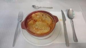 a bowl of food on a plate next to a fork and knife at Hostal Restaurante San Millan in Orihuela del Tremedal