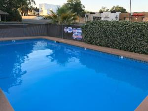 a swimming pool with blue water in front of a fence at Red Bluff Inn in Red Bluff +17 photos