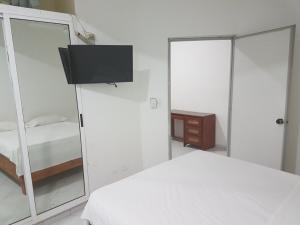 a white bedroom with a bed and a mirror at Hotel Costa Linda Beach Boca Chica in Boca Chica
