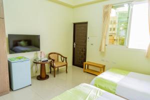a bedroom with two beds and a tv and a chair at Just Stay 稼軒 in Yuanshan