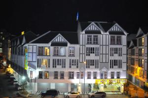 a large white building with cars parked in front of it at Hotel Double Stars Cameron Highlands in Cameron Highlands