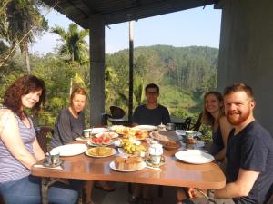 un grupo de personas sentadas alrededor de una mesa con comida en Isuru Homestay, en Ella