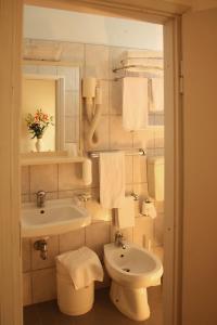 ein Badezimmer mit einem Waschbecken, einem WC und einem Spiegel in der Unterkunft Hotel Santiago in Milano Marittima