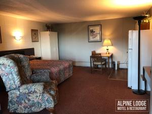 a hotel room with a bed and a couch and a table at Alpine Lodge Motel & Restaurant in Grande Cache