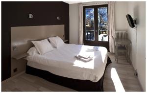 a bedroom with a large white bed with a window at La Bonne Auberge in Risoul