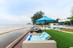 uma fila de cadeiras azuis e um guarda-sol junto à praia em My Vimarn Hua Hin em Hua Hin