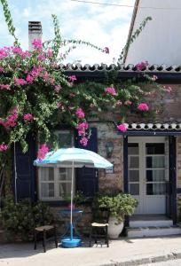 a blue umbrella sitting in front of a house with pink flowers at To Spitaki Apartments in Galaxidhion