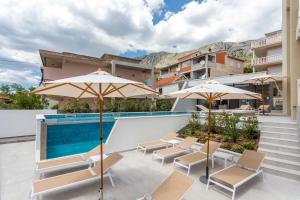 eine Terrasse mit Stühlen und Sonnenschirmen neben einem Pool in der Unterkunft Villa Mandalinic in Omiš