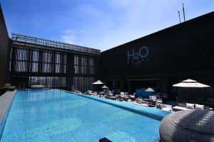 高雄水京栈国际酒店 的建筑物旁边有带椅子和遮阳伞的游泳池