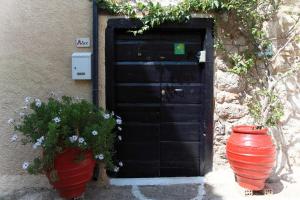 a black door with two large vases in front of it at To Spitaki Apartments in Galaxidhion