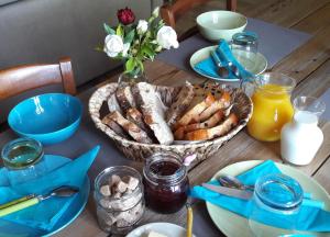 a table with a basket of bread and a bowl of orange juice at Maison d'Hôtes "La Pierre Pointue" in Saint-Léons