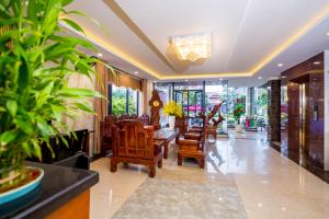 a lobby with chairs and a table and some plants at La Maison Danang Beach Hotel in Da Nang