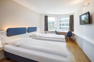 a hotel room with two beds and a television at Hotel Welcome Inn in Kloten
