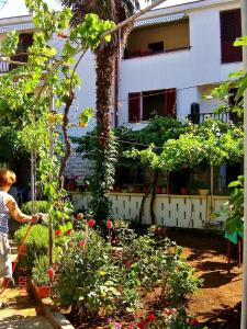 een vrouw geeft een tuin water voor een gebouw bij Apartments Stjepic in Sukošan