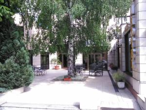 un patio con mesas, sillas y un árbol en Hotel Dinara, en Livno