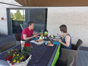 un hombre y una mujer sentados en una mesa comiendo comida en B&B Appelkers II en Kortessem