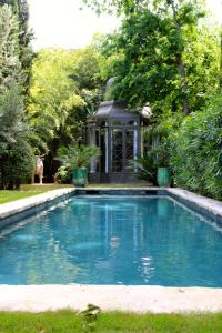 a swimming pool in front of a house with trees at La Divine Comédie-Suites Deluxe in Avignon