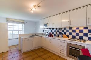 a kitchen with white cabinets and blue and white tiles at Boa Vida in Quarteira