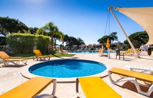 a swimming pool with yellow chairs and an umbrella at Boa Vida in Quarteira